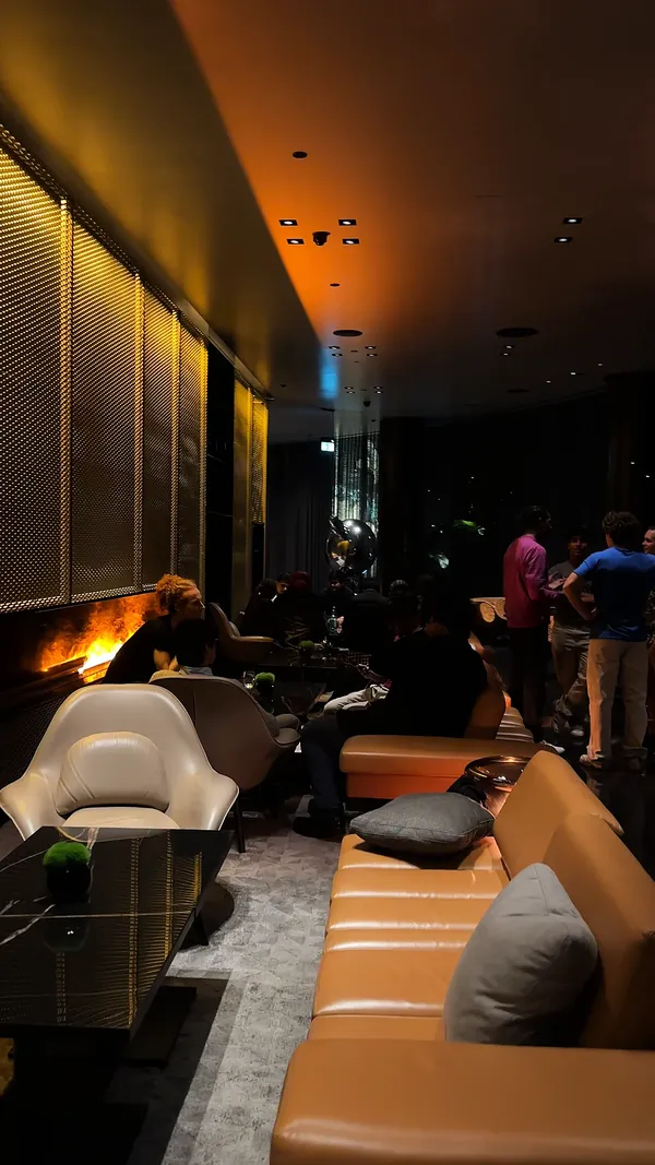 A dim London lounge with leather sofas and a fire, young founders talking in groups